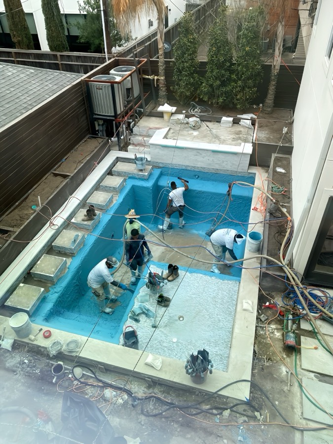 Pool renovation crew applying new plaster during a Suns Out Buns Out Pools remodel