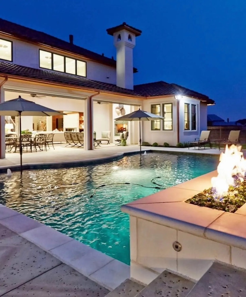 Renovated pool with fire feature glowing at dusk